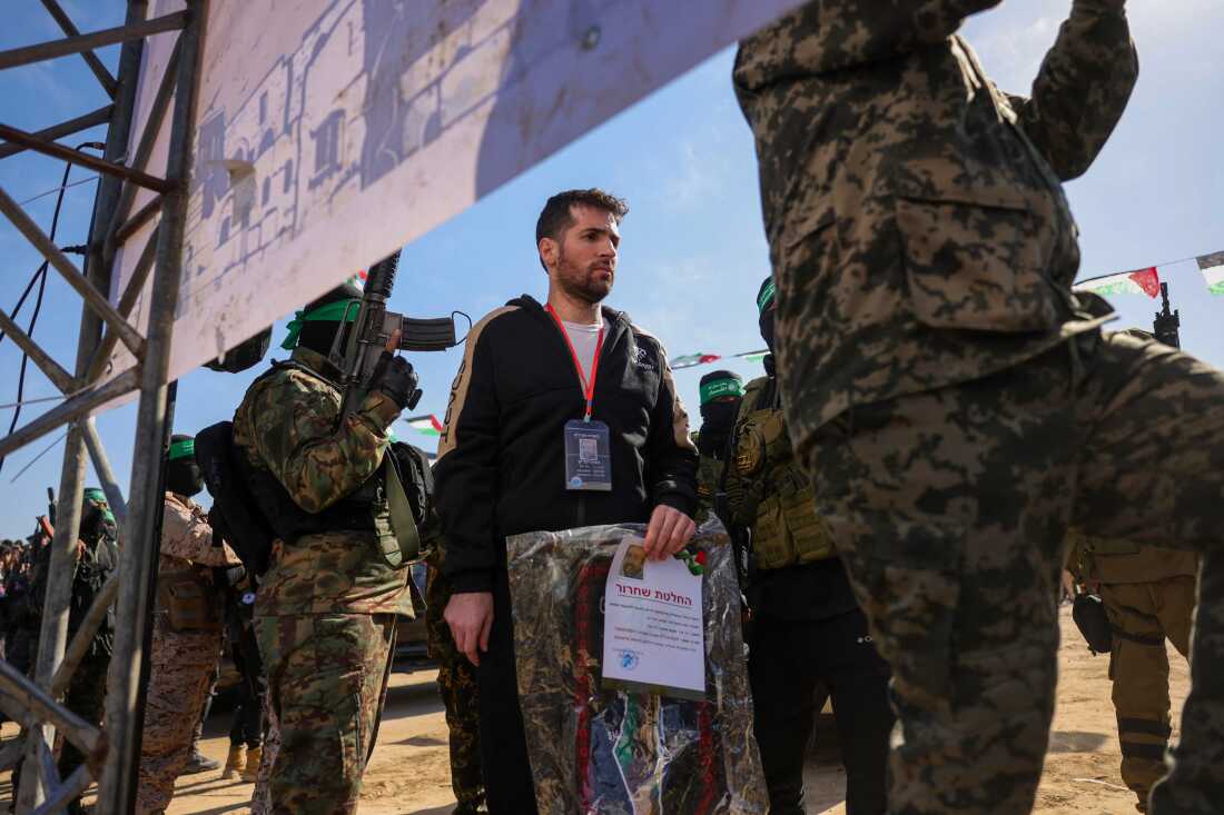 Hamas militants escort Israeli-American hotsage Sagui Dekel-Chen on a stage before handing him over to a Red Cross team in Khan Yunis, southern Gaza Strip, on February 15, 2025, as part of the sixth hostage-prisoner exchange. (Photo by Bashar TALEB / AFP)