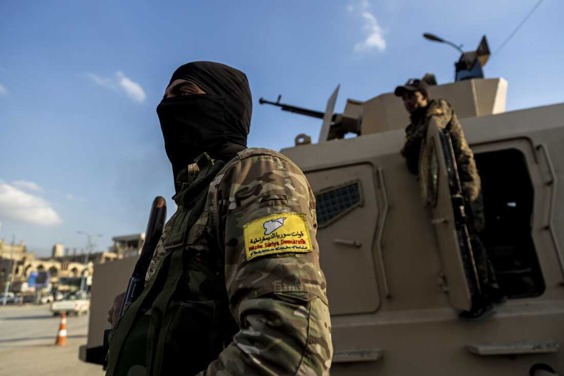 U.S.-backed Syrian Democratic Forces (SDF) fighters stand guard at Al Naeem Square, in Raqqa, Syria, Monday, Feb. 7, 2022. Once the capital of the Islamic State group, Raqqa is now free, but its residents are fighting to leave. (AP Photo/Baderkhan Ahmad) 