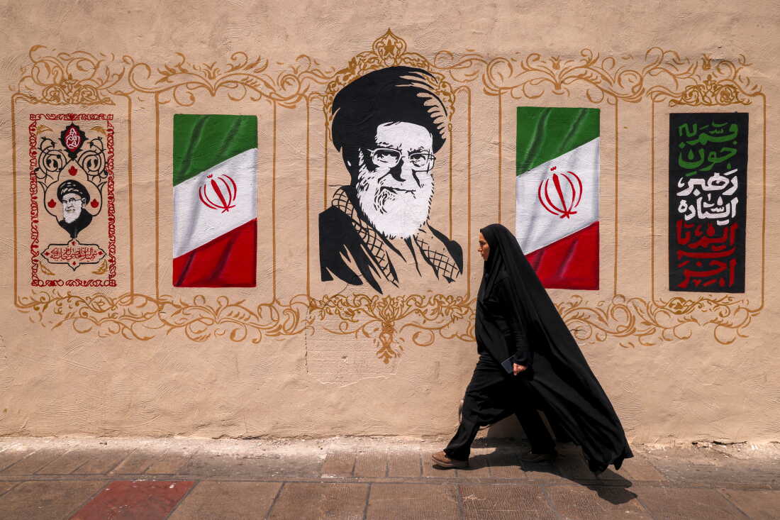 A woman walks past a mural depicting Iran's late supreme leader Ali Khamenei at Valiasr Square in central Tehran on August 8, 2026. Hopes for an imminent US-Iran deal to end the blockage of the Strait of Hormuz added to optimism that oil and gas, along with other key products, would again start flowing freely after more than five months of war. But oil prices turned higher ahead of the weekend in the absence of any confirmation of an accord, amid reports that Iran was planning to block US and Israeli ships from the waterway. (Photo by ATTA KENARE / AFP) / 
