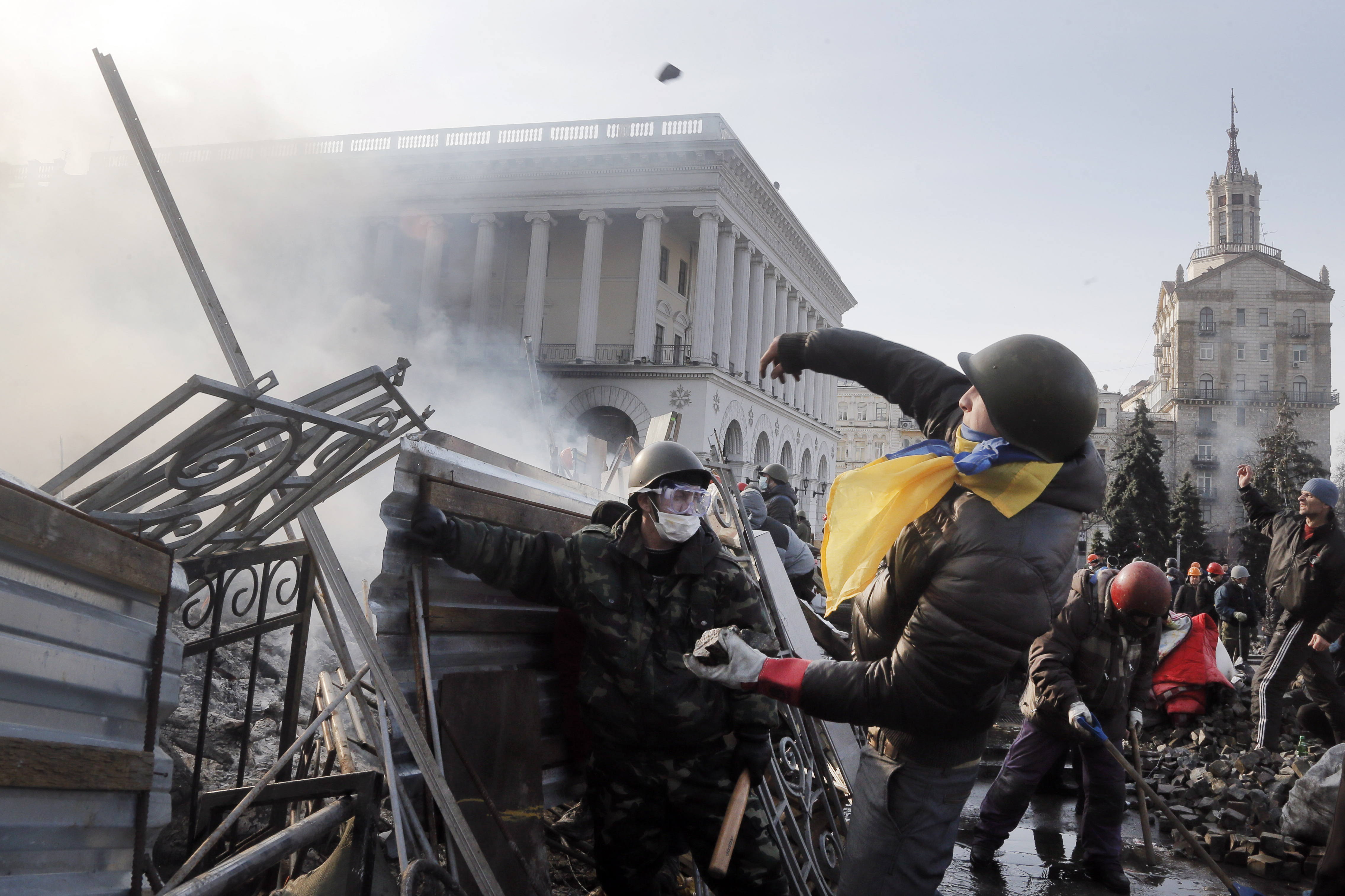 An anti-government protester throws a stone during clashes with riot police in Kiev's Independence Square, the epicenter of the country's current unrest, Kiev, Ukraine, Wednesday, Feb. 19, 2014. The deadly clashes in Ukraine’s capital have drawn sharp reactions from Washington, generated talk of possible European Union sanctions and led to a Kremlin statement blaming Europe and the West.  (AP Photo/Efrem Lukatsky)