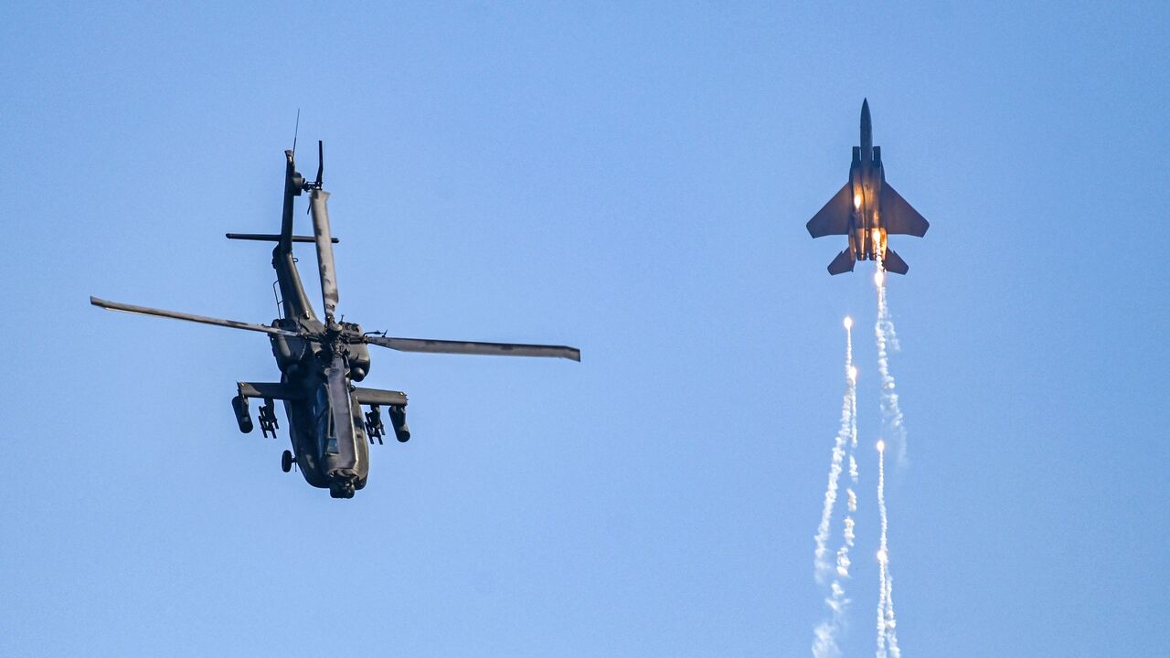 Singaporean Air Force's F15SG fighter jet and Apache helicopter (L) perform during a preview of the Singapore Airshow in Singapore on February 18, 2024. (Photo by Roslan RAHMAN / AFP)