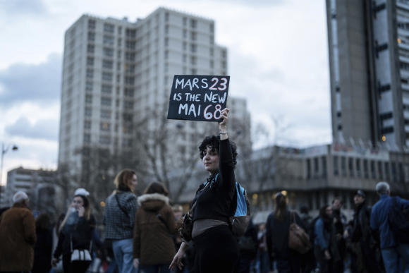 A protester holds a banner during a protest in Paris, Saturday, March 18, 2023. A spattering of protests were planned to continue in France over the weekend against President Macron's controversial pension reform, as garbage continued to reek in the streets of Paris and beyond owing to continuing action by refuse collectors. (AP Photo/Lewis Joly)