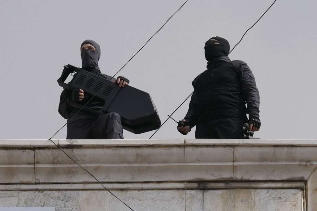 Hezbollah fighters stand guard on a building roof top to protect their supporters during a protest to show their solidarity with the Palestinians, in the southern suburb of Beirut, Lebanon, Friday, Oct. 13, 2023. Tens of thousands of Muslims demonstrated Friday across the Middle East in support of the Palestinians and against Israeli airstrikes pounding Gaza, underscoring the risk of a wider regional conflict erupting as Israel prepares for a possible ground invasion in the coastal strip. (AP Photo/Hussein Malla)