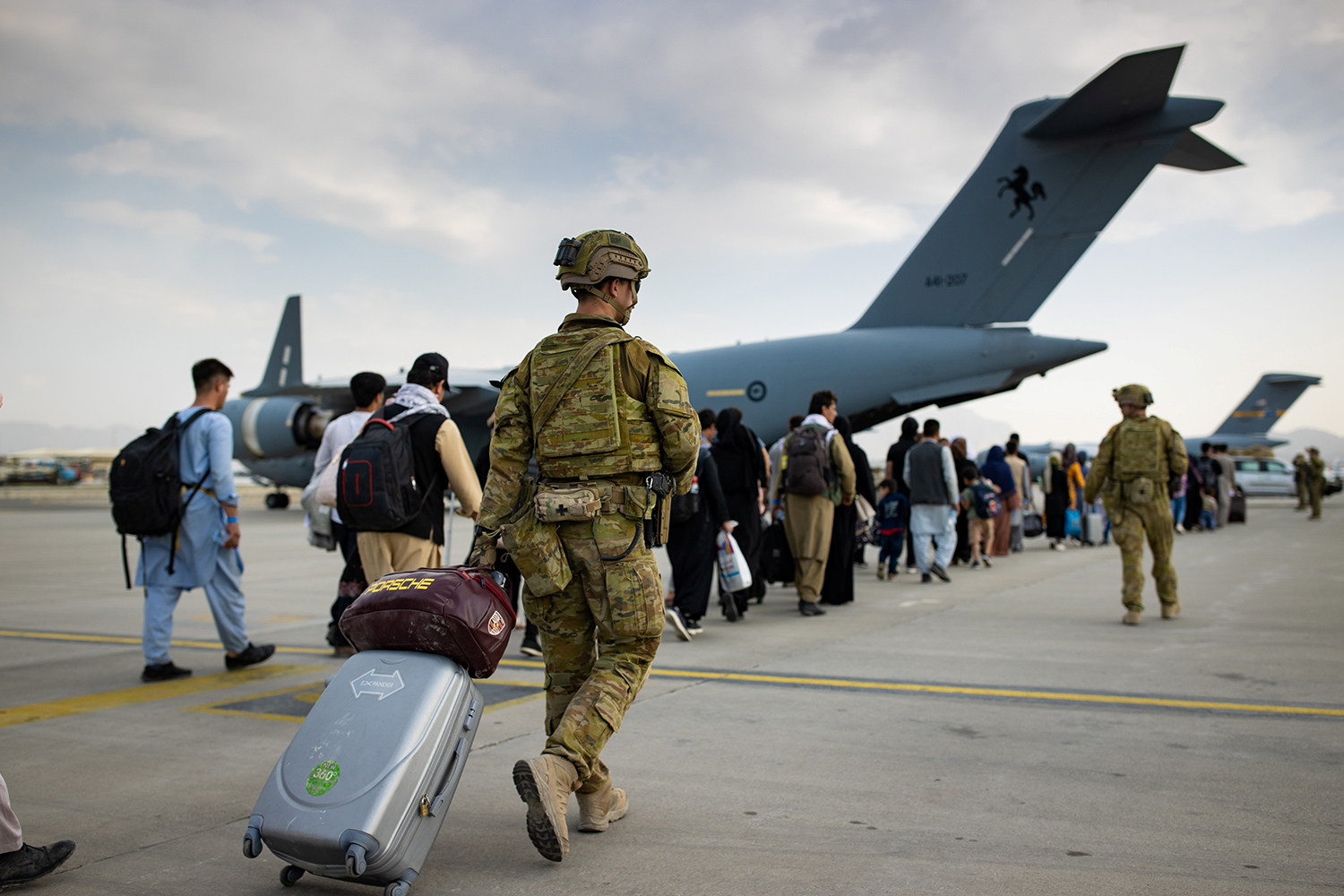 Australian citizens and visa holders prepare to board the Royal Australian Air Force C-17A Globemaster III aircraft, as Australian Army infantry personnel provide security and assist with cargo, at Hamid Karzai International Airport in Kabul, Afghanistan August 22, 2021. SGT Glen McCarthy/ Australia's Department of Defence/Handout via REUTERS. ATTENTION EDITORS - THIS IMAGE WAS PROVIDED BY A THIRD PARTY. NO RESALES. NO ARCHIVES.