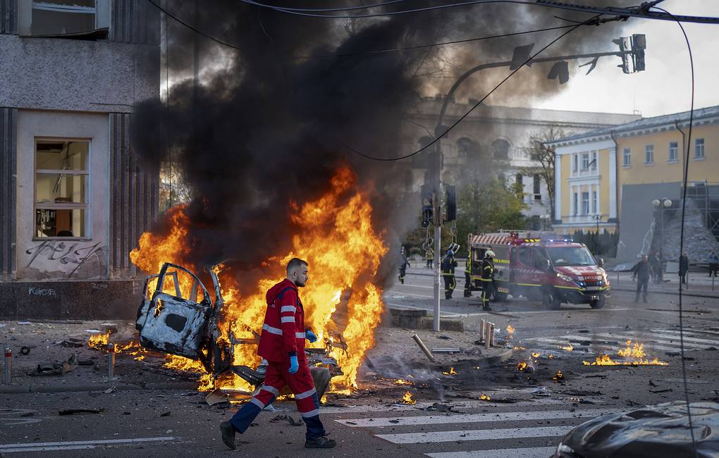 FILE - A medical worker runs past a burning car after a Russian attack in Kyiv, Ukraine, Oct. 10, 2022. The Russian missiles that rained down Monday on cities across Ukraine, bringing fear and destruction to areas that had seen months of relative calm, are an escalation in Moscow's war against its neighbor. But military analysts say it's far from clear whether the strikes mark a turning point in a war that has killed thousands of Ukrainians and sent millions fleeing from their homes. (AP Photo/Roman Hrytsyna, File)
