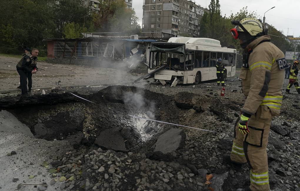 FILE - Firefighters and police officers work at a site where an explosion created a crater on the street after a Russian attack in Dnipro, Ukraine, Monday, Oct. 10, 2022. (AP Photo/Leo Correa, File)