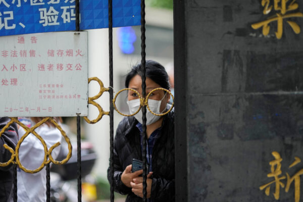 FILE PHOTO: A resident waiting for a food delivery looks out from behind a gate blocking an entrance to a residential area under lockdown amid the coronavirus disease (COVID-19) pandemic, in Shanghai, China April 13, 2022. REUTERS/Aly Song